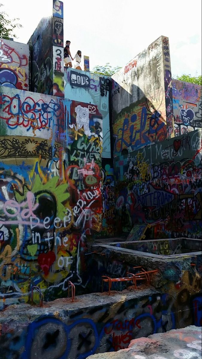 a man riding a skateboard down the side of a ramp covered in grafitti