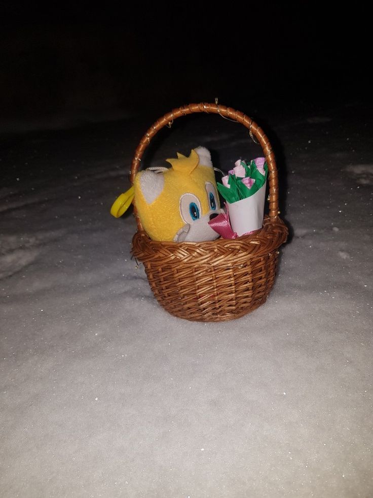 a basket filled with stuffed animals sitting in the snow