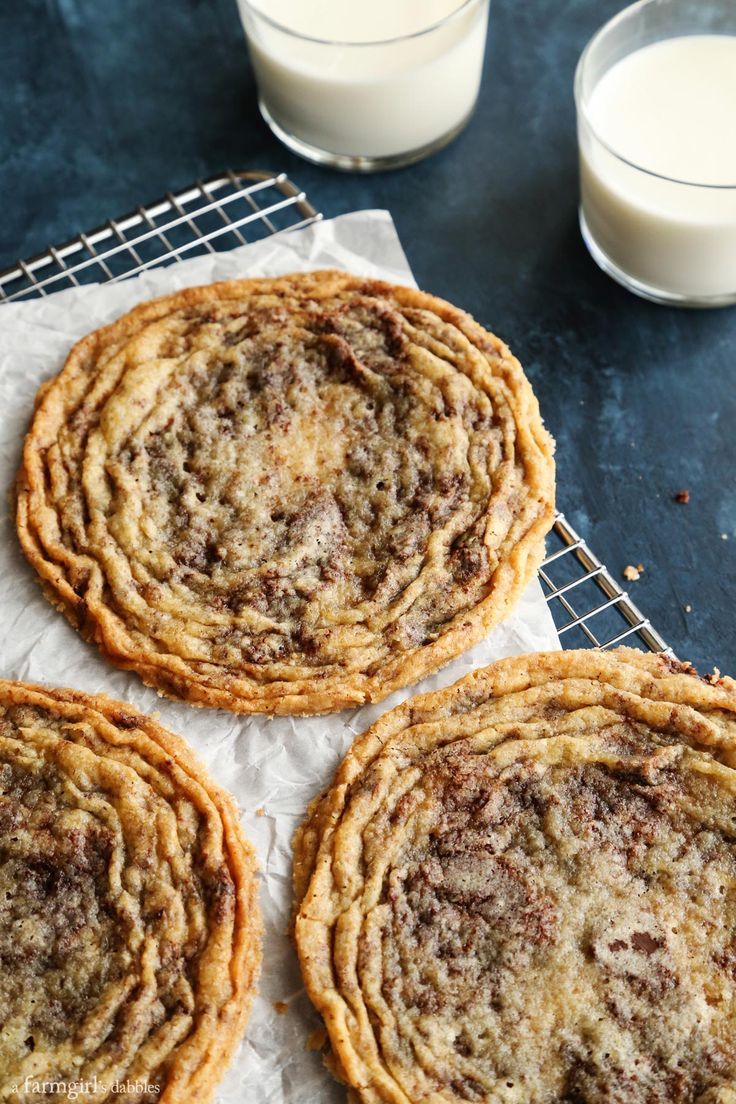 three cookies sitting on top of a cooling rack next to a glass of milk