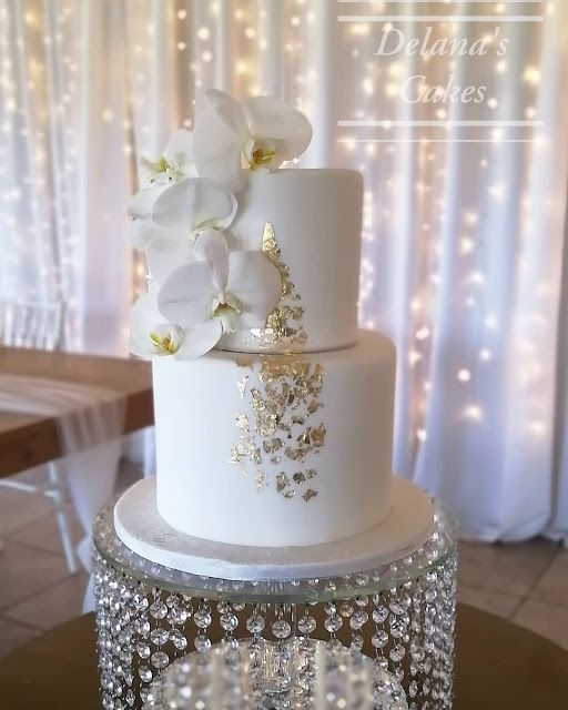 a three tiered white cake with flowers on top and sparkling decorations around the edges