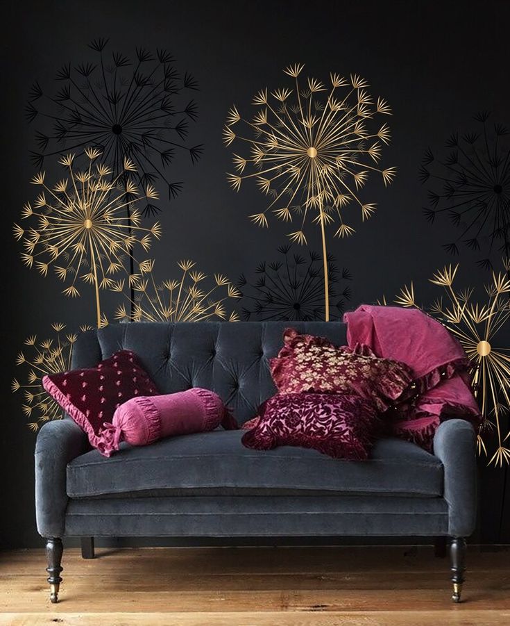 a couch with some pillows on it in front of a wall decorated with dandelions