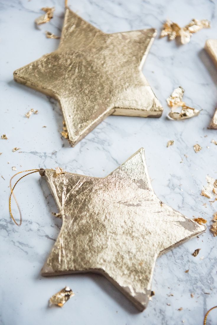 three gold star ornaments on a marble surface