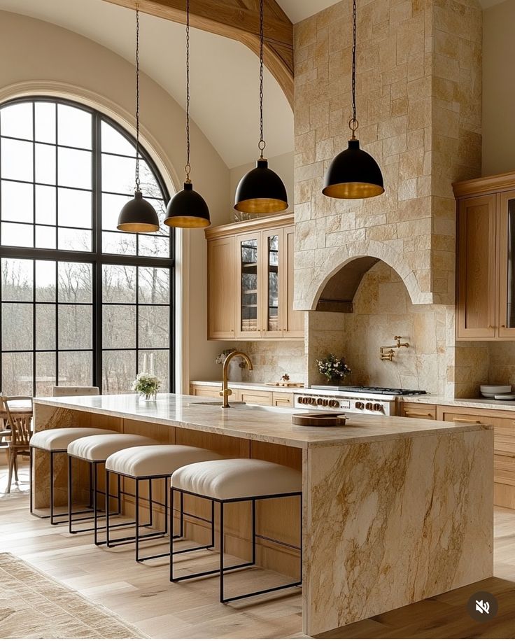 a large kitchen with marble counter tops and stools in front of an arched window