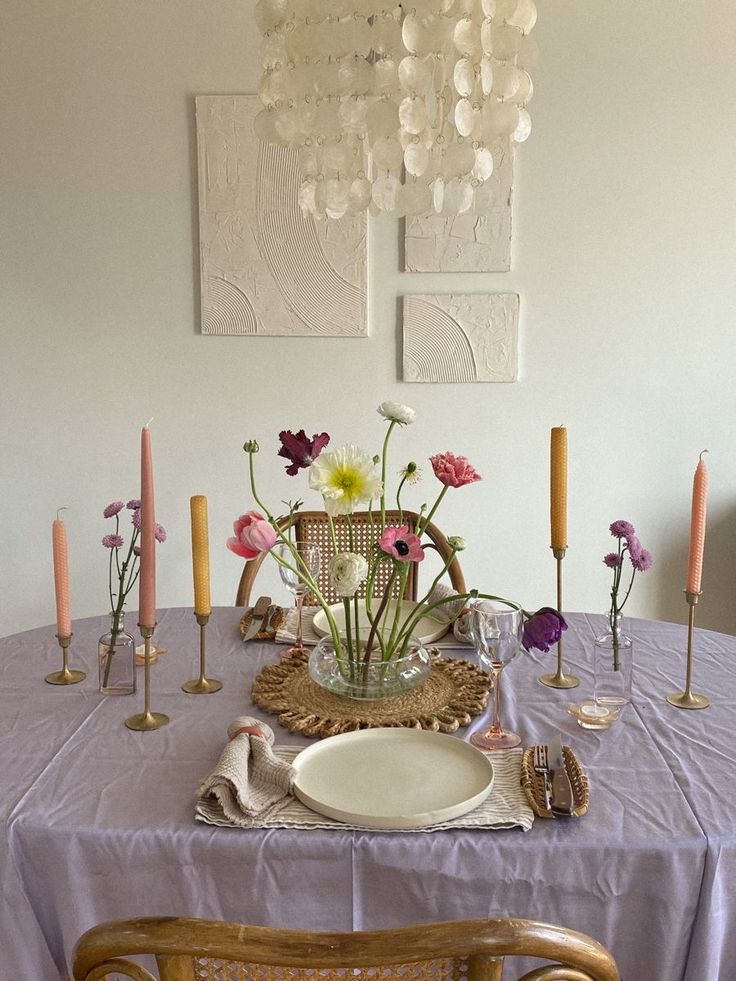 a dining room table is set with flowers and candles