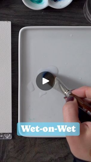 a person is using a brush to paint on a white tray with watercolor paints