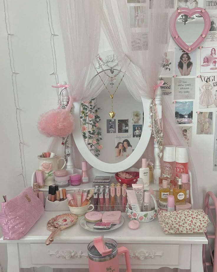 a white desk topped with lots of pink furniture and decorating items in front of a mirror