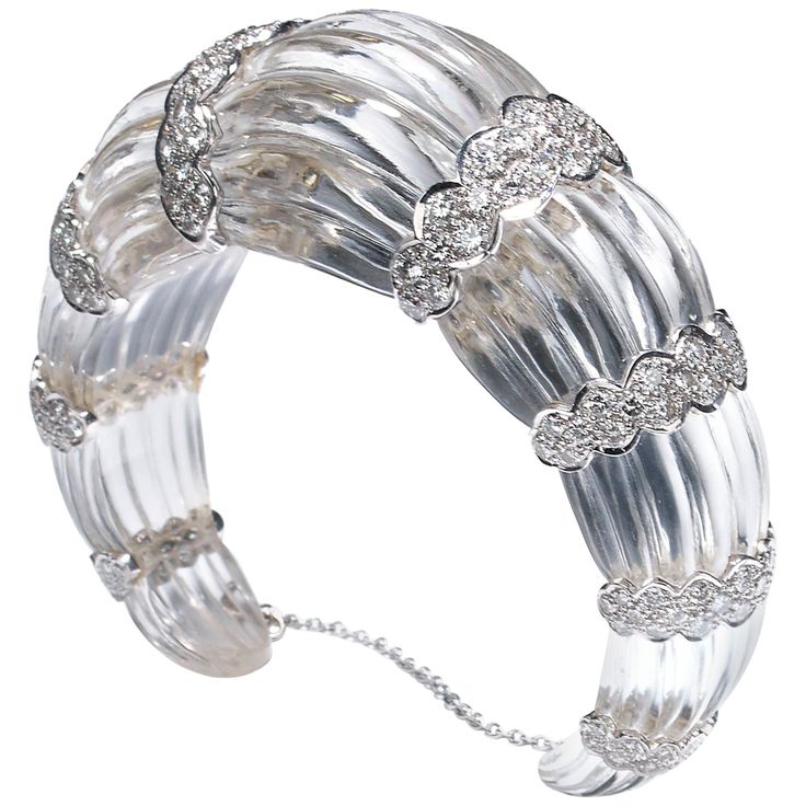 A modern, fluted rock crystal bangle bracelet, carved from one single piece of rock crystal, with eight scalloped 18ct white gold sections, each set with round brilliant-cut diamonds, weighing an estimated total of 7.00 carats. With a white gold safety chain. Approximate wrist measurement: 171mm Modern Bangle, Diamond Dress Ring, Diamond Tops, Diamond Cuff Bracelet, Three Stone Diamond Ring, Diamond Cluster Earrings, Platinum Earrings, Yellow Diamond Rings, Beautiful Bracelets