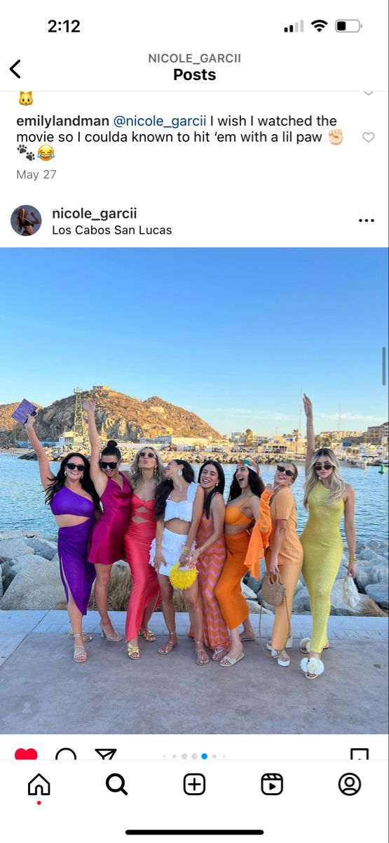 several women in dresses posing for a photo with one woman holding up her hand and the other