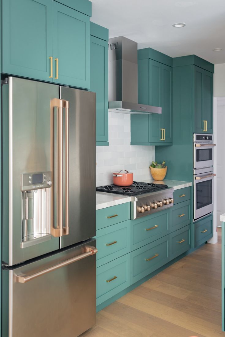 a modern kitchen with teal cabinets and stainless steel appliances