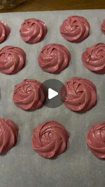 a pan filled with red frosted cookies on top of a baking sheet