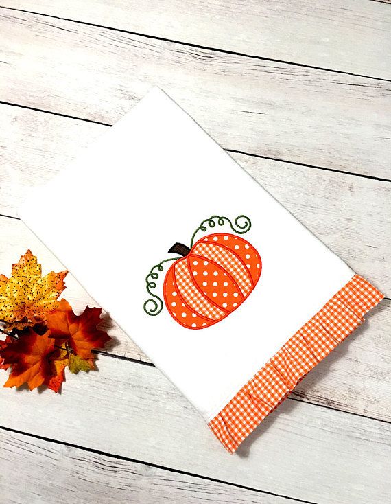 an orange and white pumpkin is sitting on a table next to some fall colored leaves