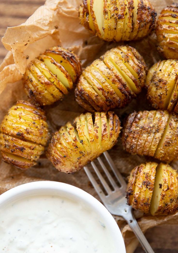 grilled potatoes on parchment paper with dip in bowl and fork next to them, ready to be eaten