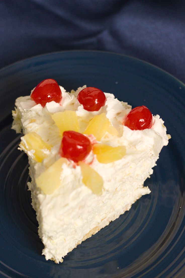 a piece of cake with pineapples and cherries is on a blue plate