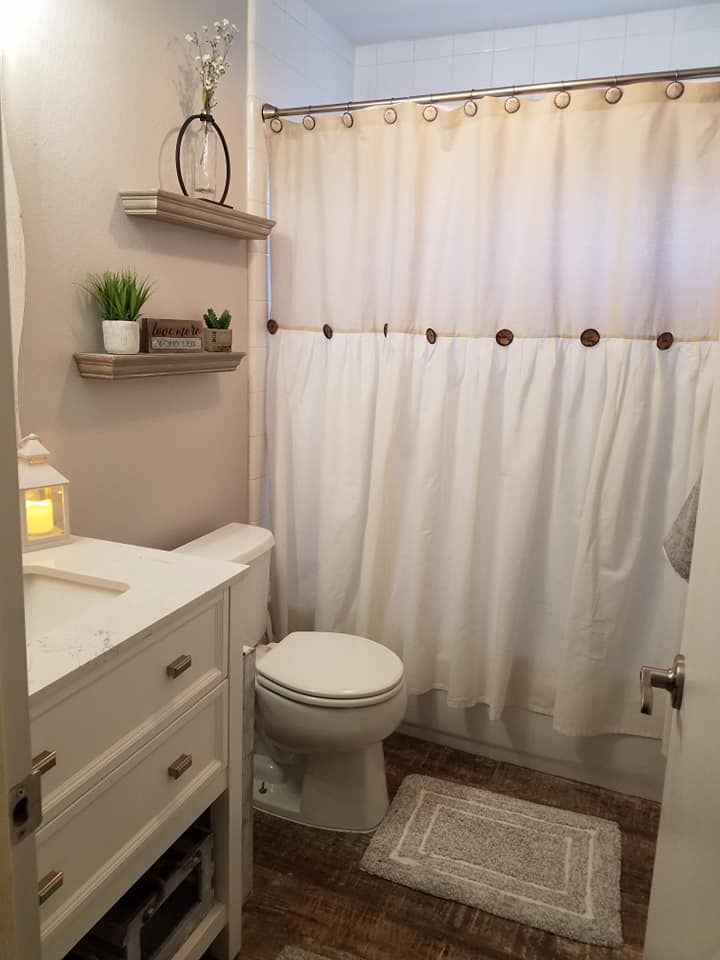 a bathroom with a sink, toilet and shower curtain in it's center area