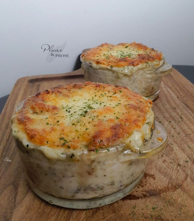 two casseroles sitting on top of a wooden cutting board