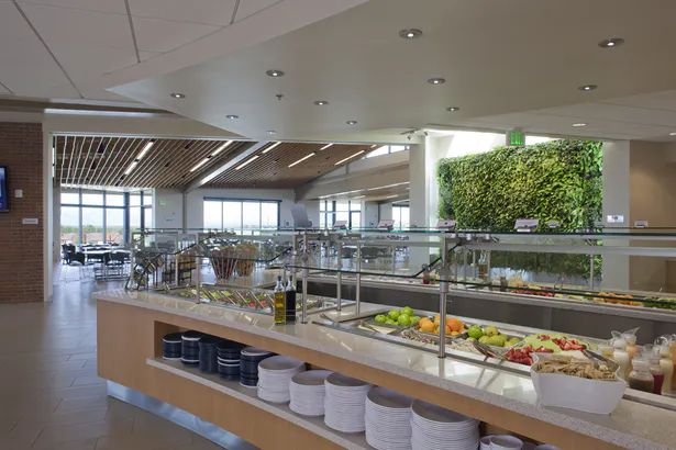 a buffet with lots of food and drinks on the counter in a large room filled with windows