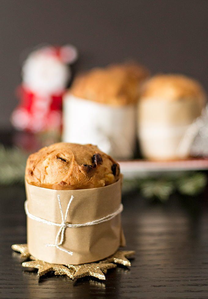 a muffin wrapped in brown paper sitting on top of a table next to some cookies