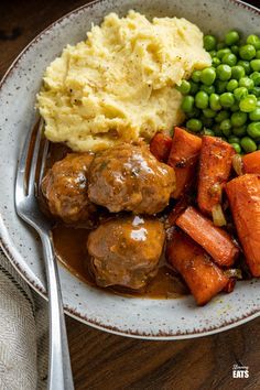 a bowl filled with meatballs, mashed potatoes and carrots next to peas