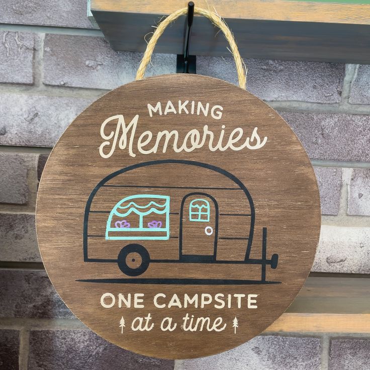 a wooden sign that says making memories one campsite at a time hanging on a brick wall