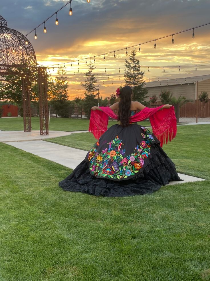 a woman is sitting on the grass with her back to the camera, wearing a colorful dress