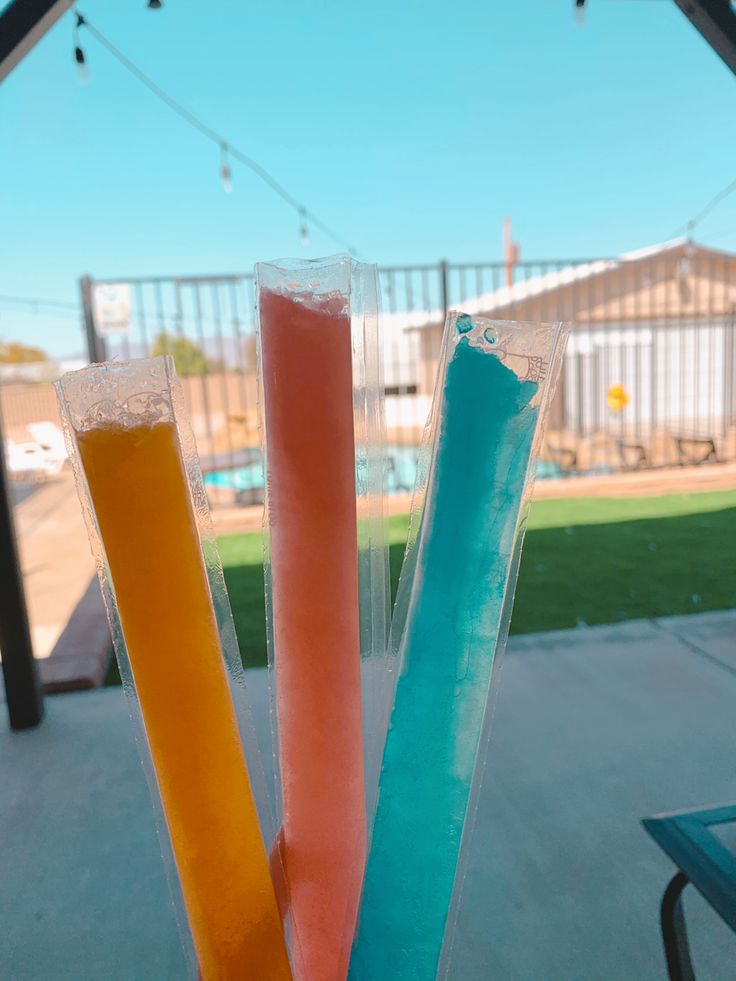 three different colored sticks sticking out of an ice cream treat in front of a pool