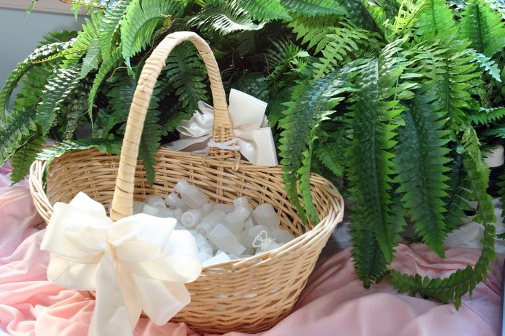 a wicker basket filled with sea glass and greenery sits on a pink blanket