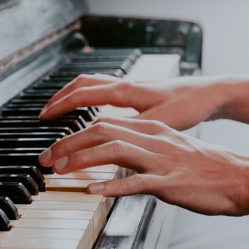 two hands are playing the piano with one hand on the keyboard, while the other is touching the keys