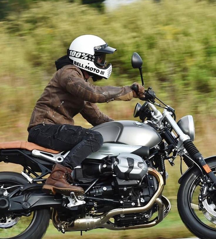 a man riding on the back of a silver motorcycle