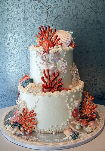 a three tiered cake decorated with corals and seashells