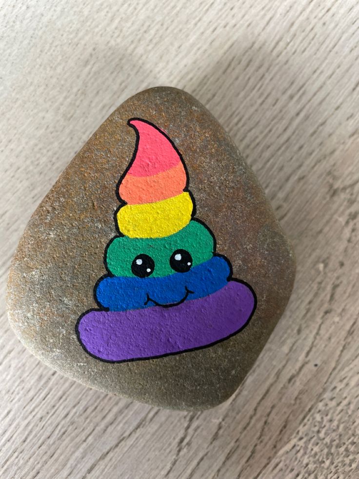 a painted rock with a rainbow ice cream cone on it, sitting on a white surface