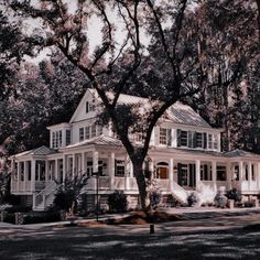 a large white house sitting on top of a lush green field next to tall trees