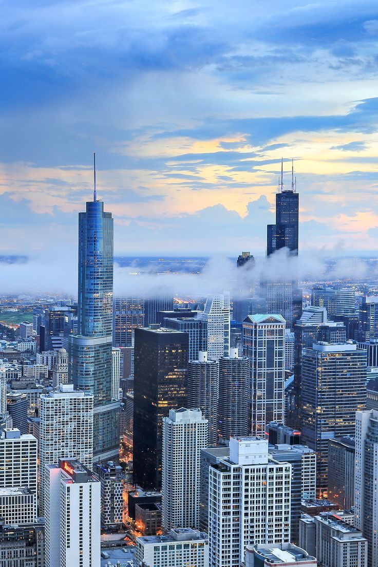 the cityscape is covered in clouds as it sits on top of a tall building