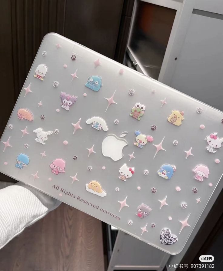 a person holding up a laptop covered in stickers with animals and stars on it