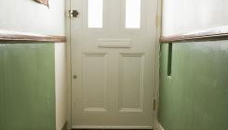 an empty hallway with green painted walls and white front door, along with two windows