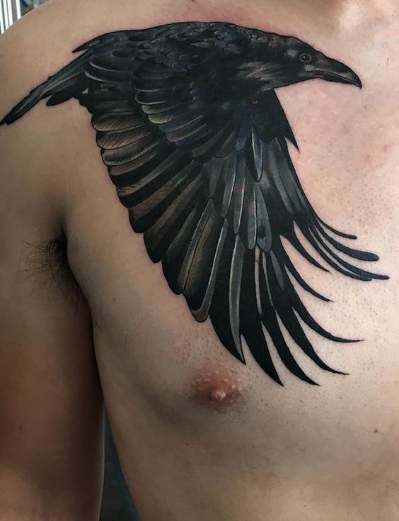 a man's chest with a black bird tattoo on his left shoulder and chest