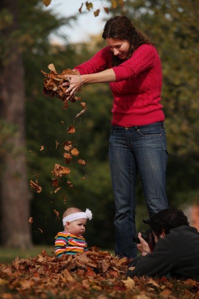 a woman is throwing leaves at a baby