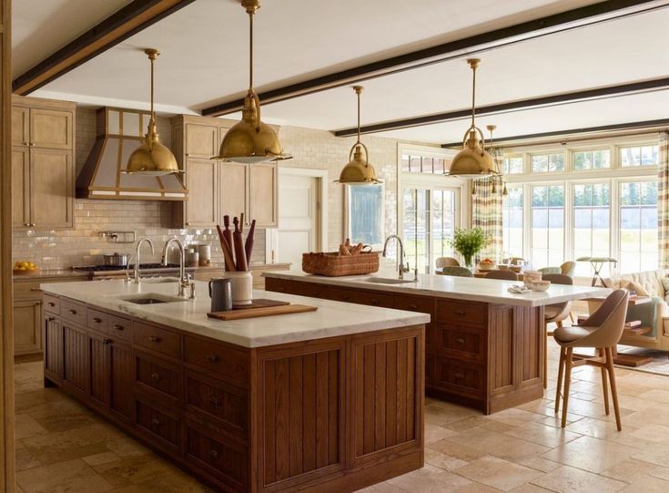 a large kitchen with an island in the middle and two pendant lights hanging from the ceiling