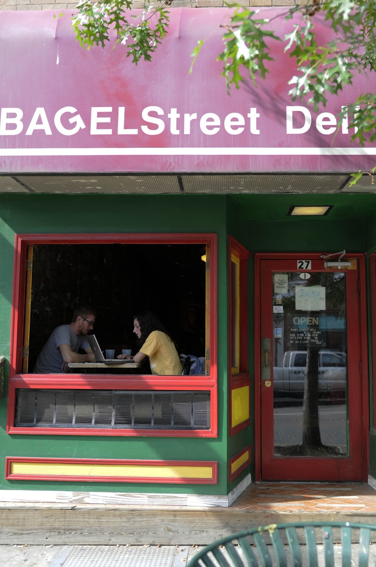 two people sitting at a table in front of a building with red and green trim