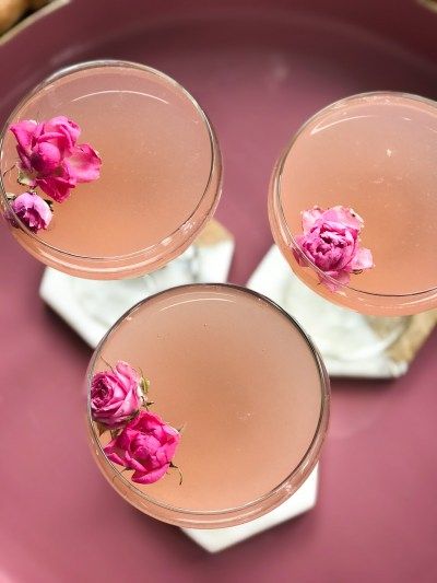 three glasses filled with drinks sitting on top of a purple plate next to some crackers