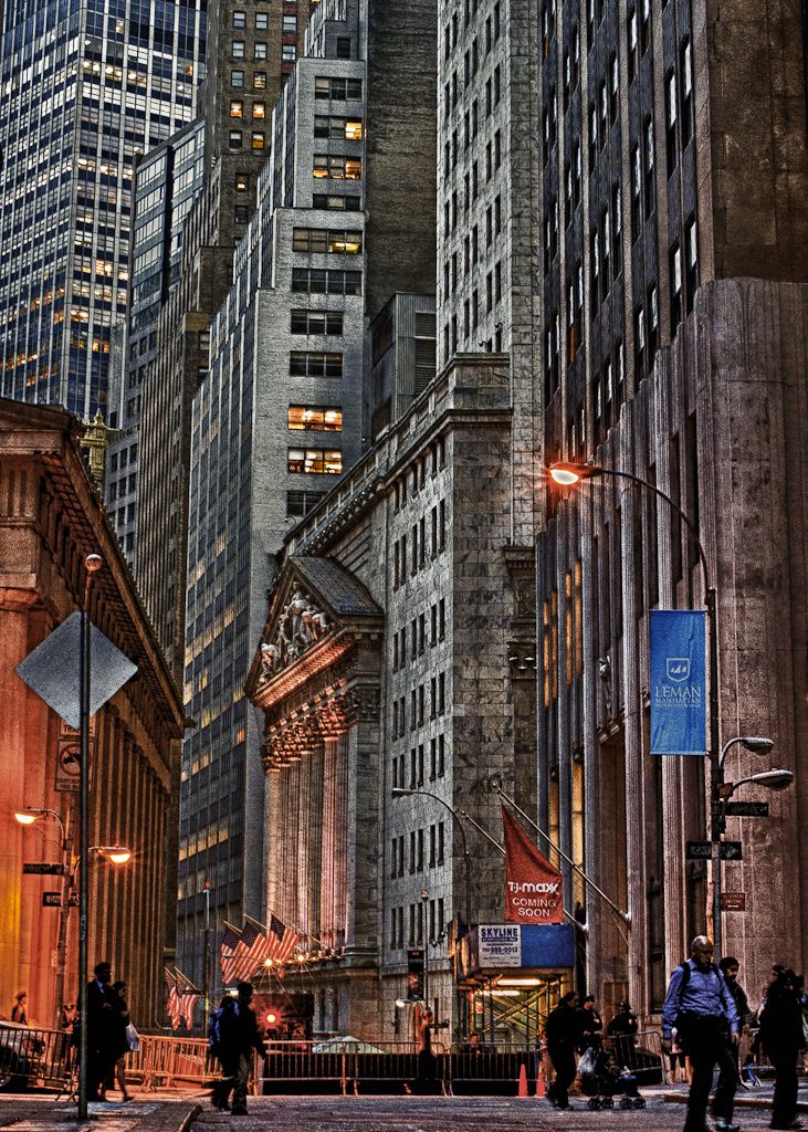 a city street filled with lots of tall buildings and people walking on the side walk