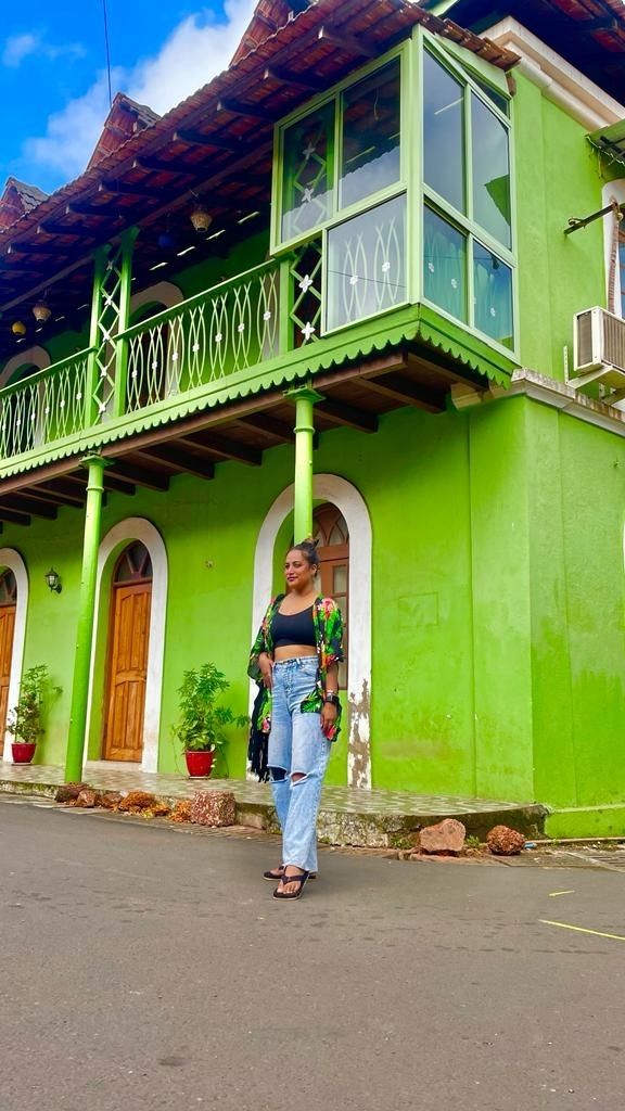 a woman standing in front of a green building with balconys and balconies