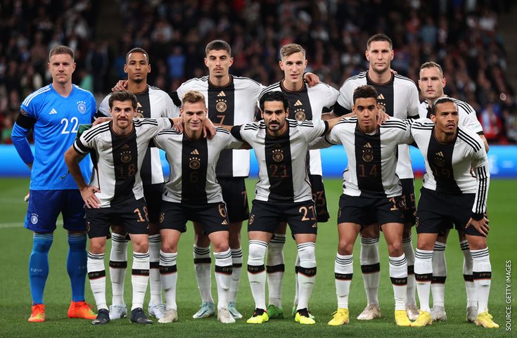 a group of soccer players pose for a team photo on the field in front of an audience