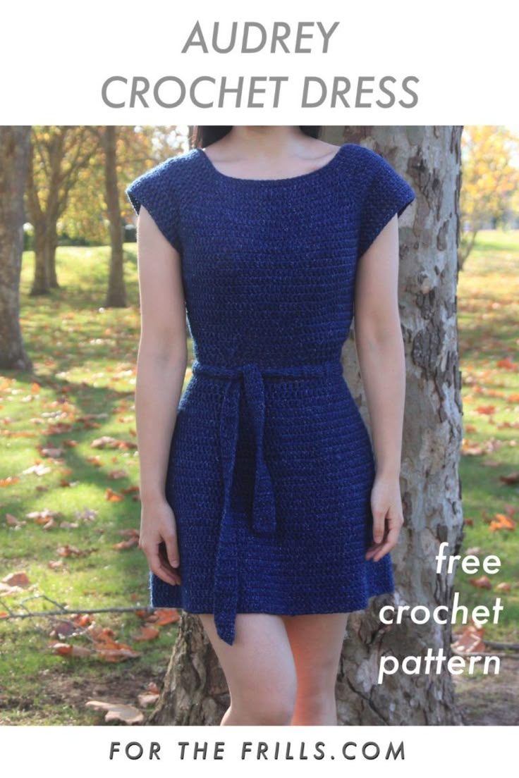 a woman standing next to a tree wearing a blue dress