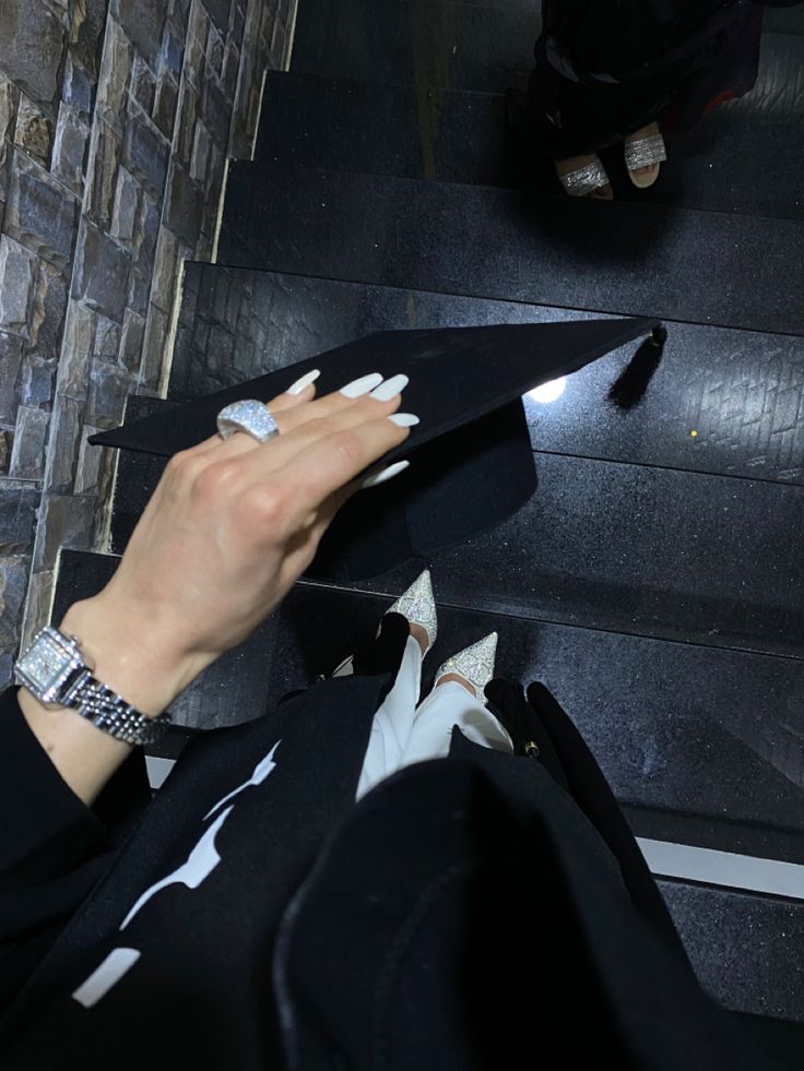 a woman with her hand on the edge of a black object in front of stairs