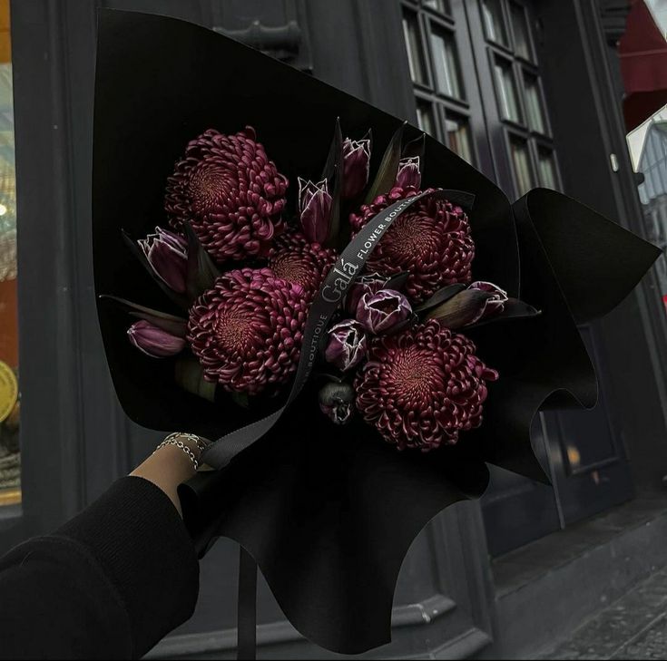 a person holding a bouquet of flowers in front of a building