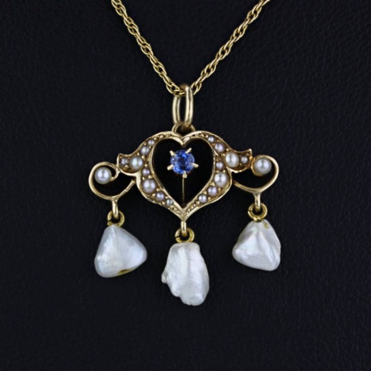 Antique Edwardian 14k Yellow Gold Sapphire + Pearl Heart Pendant Necklace This Antique Pendant + Necklace Combination Is Made Of 14 Karat Yellow Gold & Features A Heart-Shaped Pendant With An Edwardian-Style Design. Contains 1 Round-Cut Sapphire Stone In The Center Of The Heart, 16 Seed Pearls & 3 Freshwater Pearls Dangling From The Bottom. The Chain Is Measured At 20 Inches From End To End & Is Held Together By A Spring Ring Clasp. "14b" Is Stamped On The Back Of The Pendant & "14k" Is Stamped Onto A Section Of The Chain's Closure. Size: 20" Length Metal: 14 Karat Yellow Gold Stones: 1 Sapphire (2.7mm), 16 Seed Pearls, 3 Freshwater Pearls Weight: 2.15dwt // 3.35g (I-3408)* E-1247 Victorian White Gold Pendant Necklace, Antique White Gold Necklace With Pearl Pendant, White 14k Gold Filigree Jewelry, Victorian White Gold Necklace For Anniversary, White Gold Victorian Necklace For Anniversary, Victorian Style White Gold Necklace For Anniversary, Antique Heart-shaped 14k Gold Necklace, Antique Yellow Gold Heart Necklace, Victorian 14k Gold Heart-shaped Jewelry