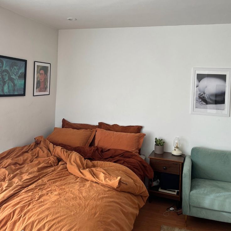 a bedroom with a bed, chair and pictures on the wall above it is shown