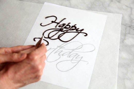 someone is writing happy birthday on a piece of paper with a pen and ink brush