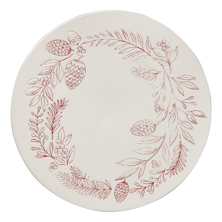 a white plate with red designs on the front and bottom, surrounded by pine cones