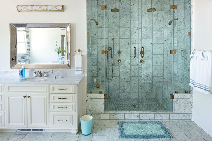 a bathroom with a walk in shower next to a white sink and blue rug on the floor